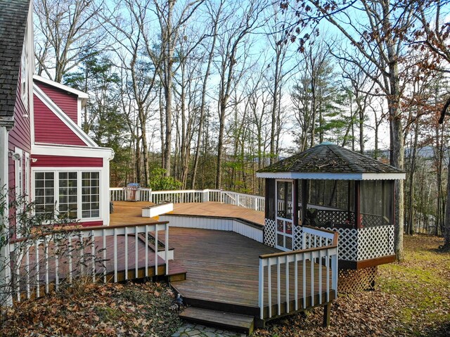 wooden deck with a gazebo and a sunroom