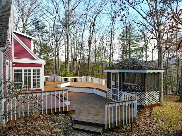 wooden deck featuring a gazebo and a sunroom