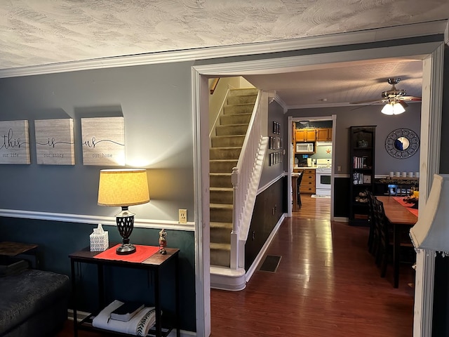 stairway with crown molding, ceiling fan, and hardwood / wood-style flooring