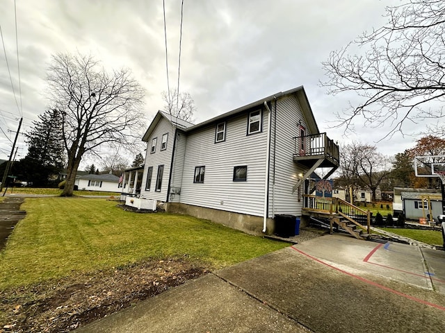 view of side of property with a balcony and a lawn