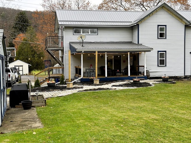 rear view of property featuring a balcony and a lawn