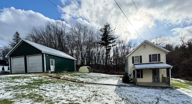 exterior space with covered porch, a garage, and a storage unit