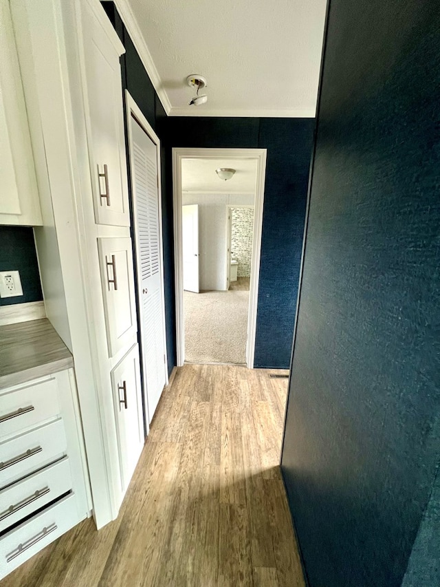 hall featuring light wood-type flooring and crown molding