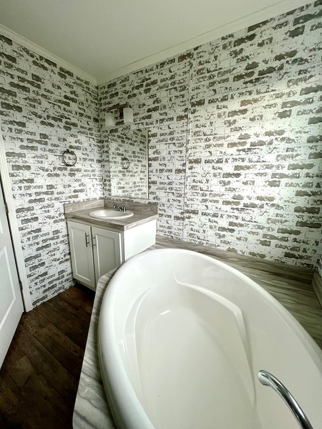 bathroom with a washtub, hardwood / wood-style floors, vanity, and ornamental molding