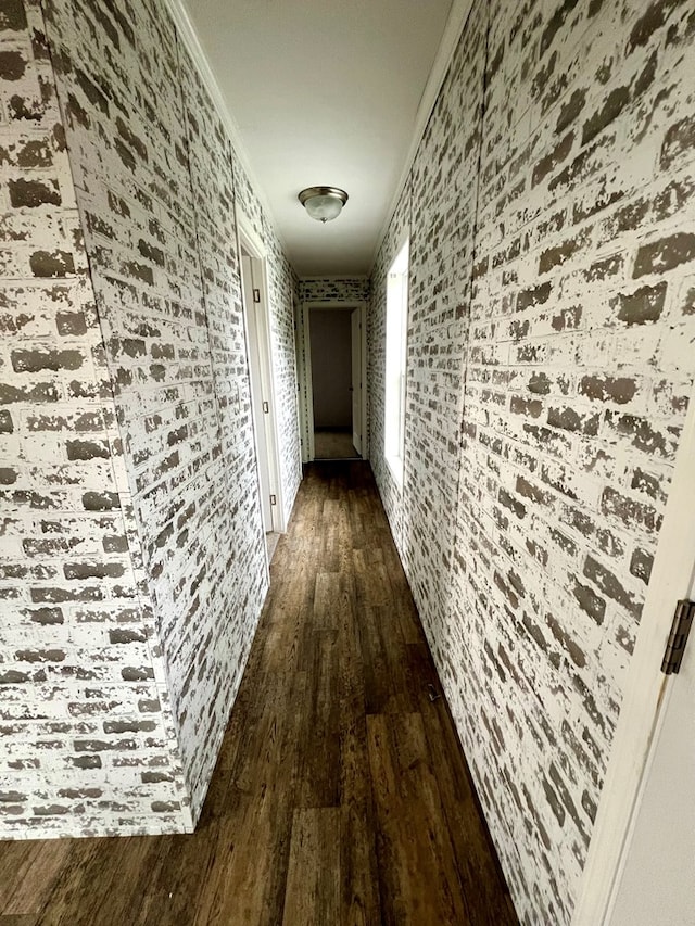 hall with dark hardwood / wood-style floors, ornamental molding, and brick wall