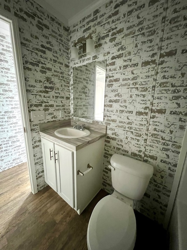 bathroom with hardwood / wood-style flooring, vanity, toilet, and crown molding