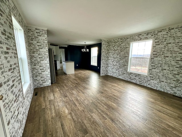 unfurnished living room featuring dark hardwood / wood-style floors, a wealth of natural light, and a notable chandelier