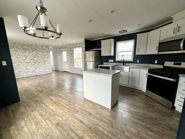 kitchen featuring sink, a center island, hanging light fixtures, white cabinets, and appliances with stainless steel finishes