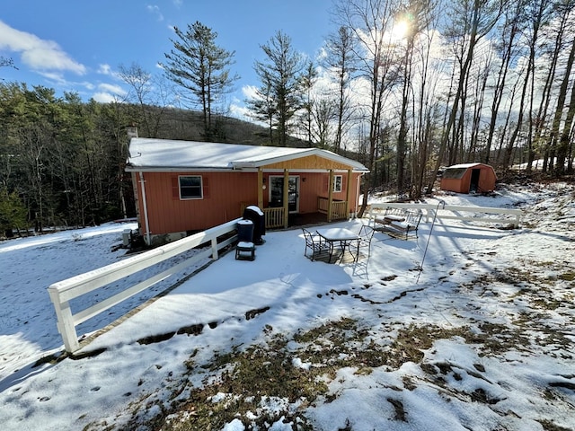 snow covered house featuring a storage unit