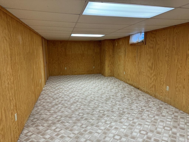 basement with a drop ceiling and wood walls