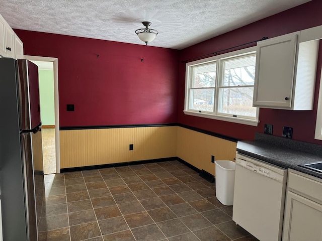 kitchen featuring stainless steel refrigerator, white cabinetry, dishwasher, and a textured ceiling