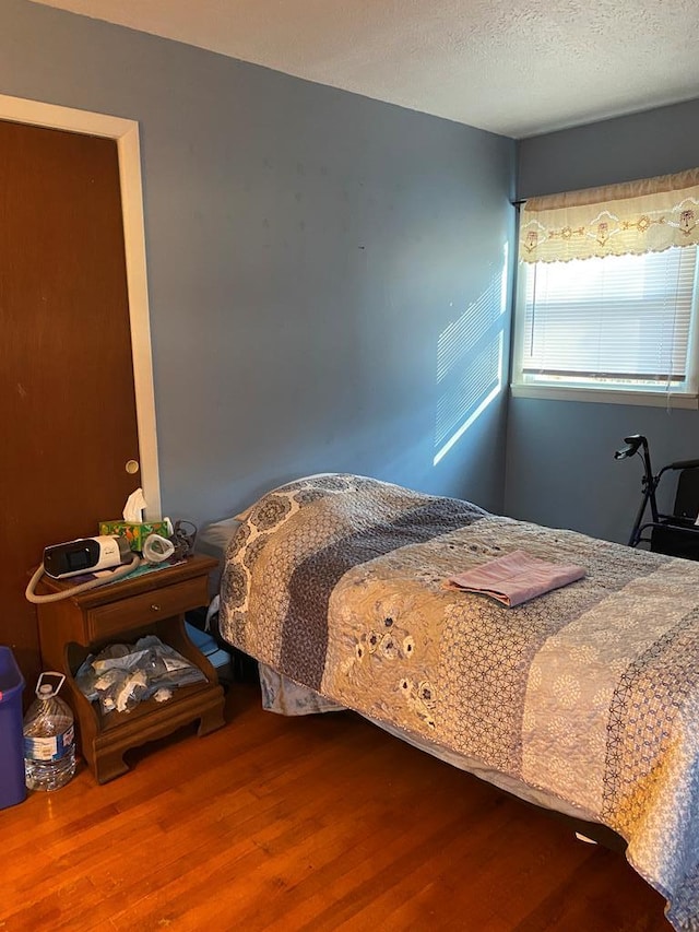 bedroom with hardwood / wood-style floors and a textured ceiling