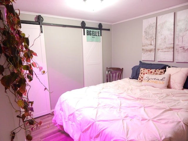 bedroom featuring hardwood / wood-style floors, a barn door, and ornamental molding