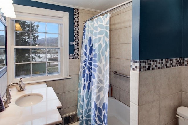 full bath with toilet, a mountain view, visible vents, vanity, and tile walls