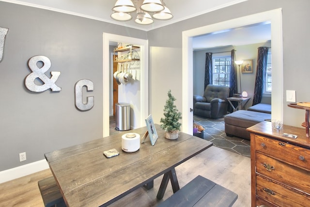 dining room with wood-type flooring, crown molding, and an inviting chandelier