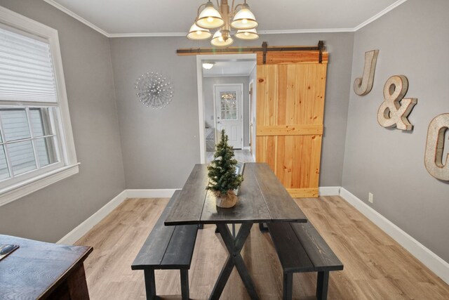 dining room featuring a barn door, light hardwood / wood-style floors, and ornamental molding