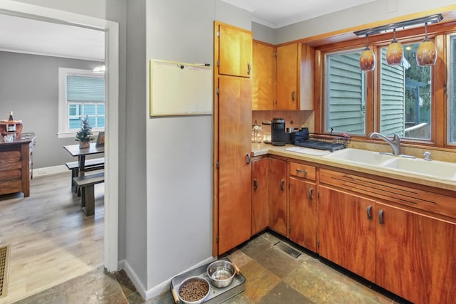 kitchen with light countertops, ornamental molding, a sink, and baseboards