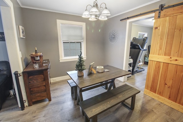 dining room featuring a chandelier, ornamental molding, a barn door, and wood finished floors