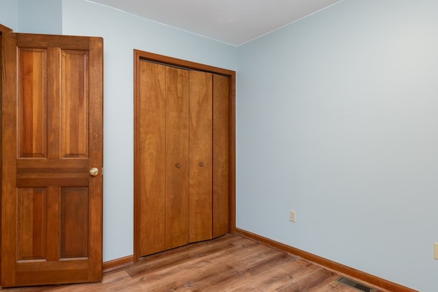 unfurnished bedroom with light wood-type flooring and a closet