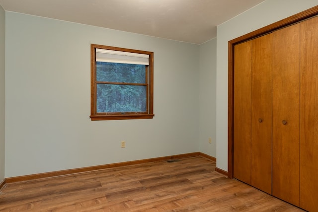 unfurnished bedroom with light wood-type flooring and a closet