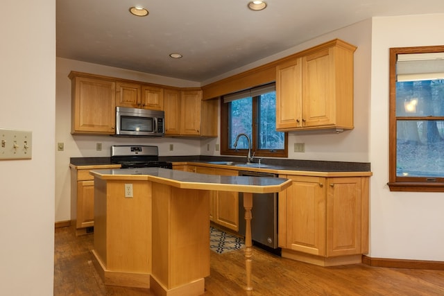 kitchen with sink, dark hardwood / wood-style flooring, a breakfast bar area, a kitchen island, and appliances with stainless steel finishes