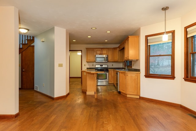 kitchen featuring pendant lighting, hardwood / wood-style flooring, a kitchen island, and appliances with stainless steel finishes