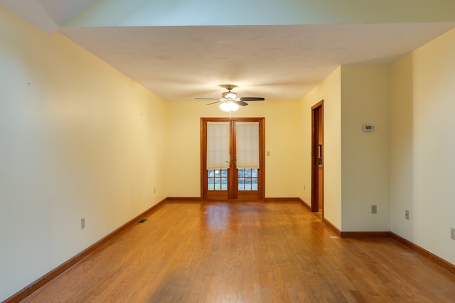 empty room with ceiling fan, french doors, and hardwood / wood-style flooring