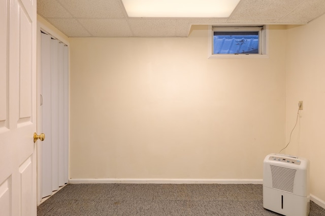 basement featuring dark carpet and a drop ceiling