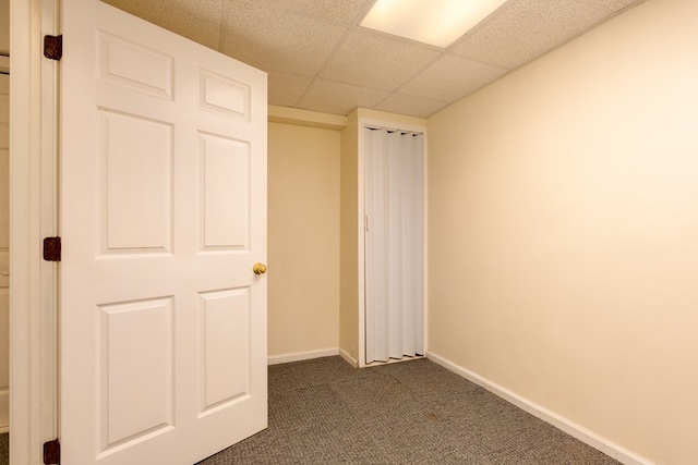 unfurnished bedroom with dark colored carpet and a drop ceiling