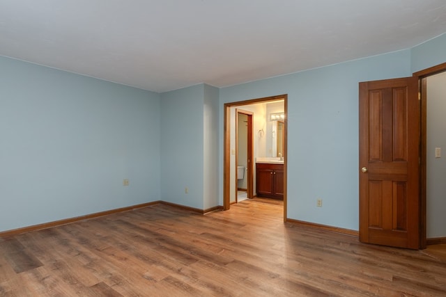 unfurnished bedroom featuring ensuite bath, sink, and light wood-type flooring