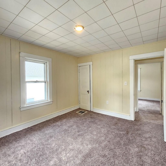 empty room with carpet and wood walls