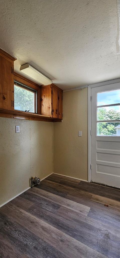 laundry area featuring a textured ceiling and dark wood-type flooring