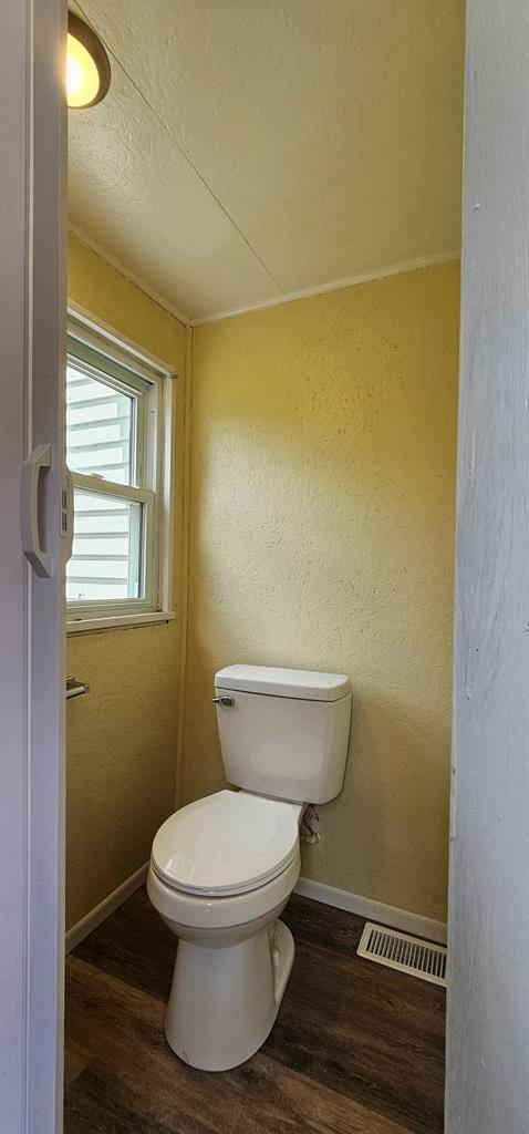 bathroom featuring hardwood / wood-style flooring, toilet, and crown molding