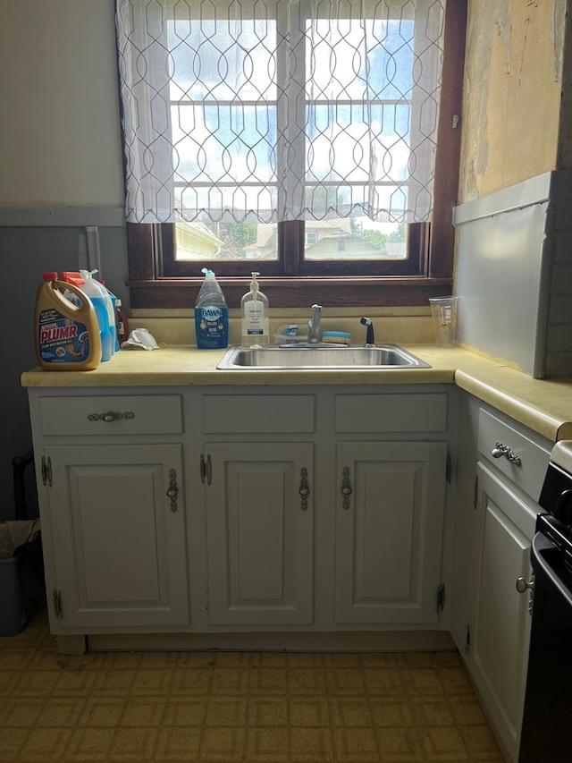 kitchen with black range oven, sink, and white cabinets