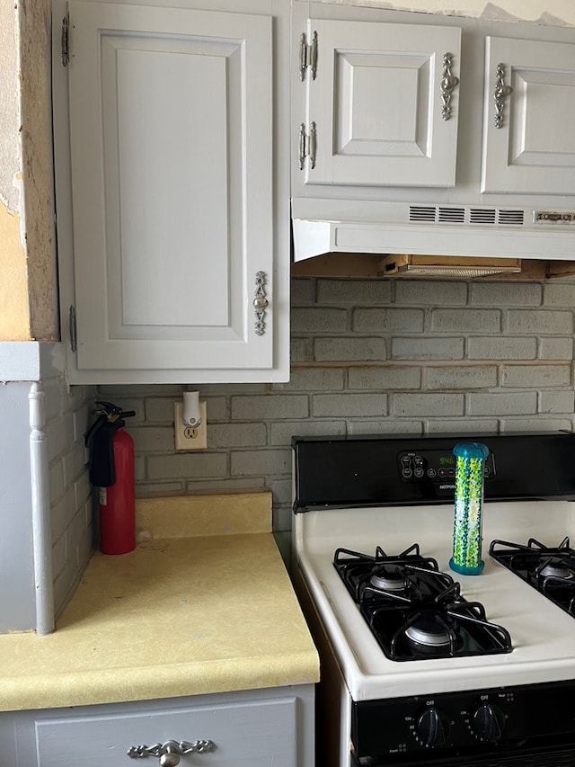 kitchen with white range with gas cooktop, white cabinetry, decorative backsplash, and ventilation hood