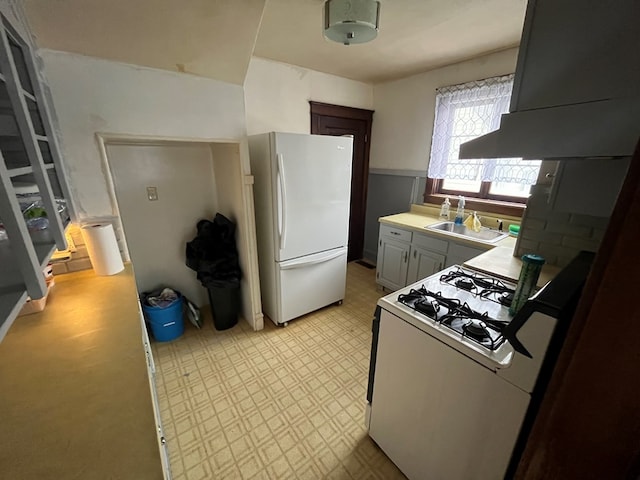 kitchen with range hood, sink, and white appliances