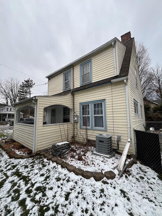 snow covered back of property featuring central AC unit