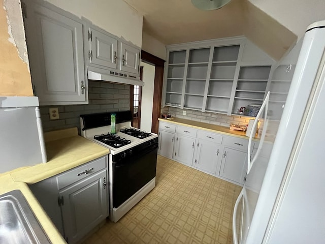 kitchen with decorative backsplash, gray cabinets, and gas range gas stove