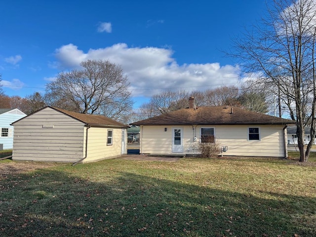 back of property featuring a yard and an outdoor structure