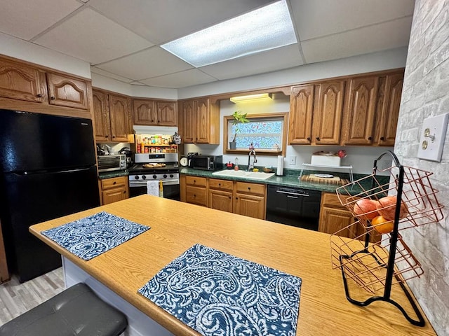 kitchen with kitchen peninsula, black appliances, a paneled ceiling, and sink