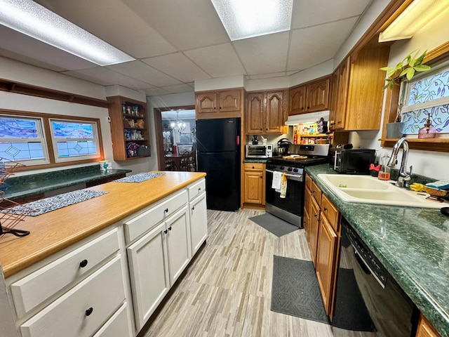 kitchen with sink, white cabinets, a drop ceiling, light hardwood / wood-style flooring, and black appliances