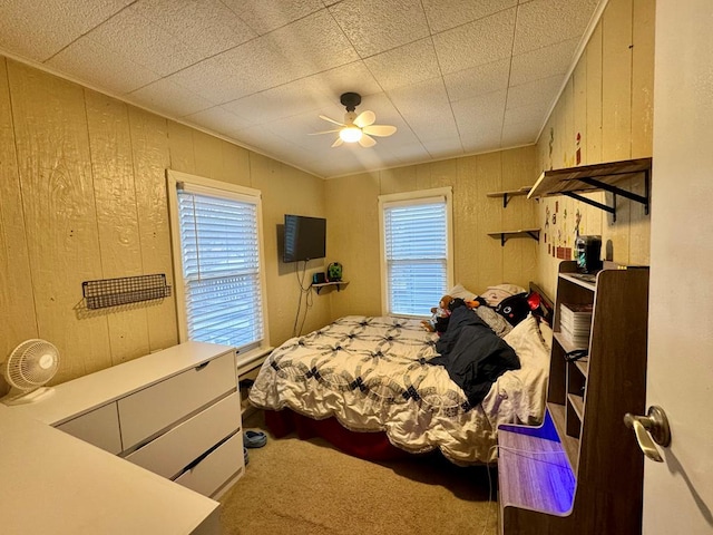 bedroom featuring wooden walls, carpet floors, and ceiling fan