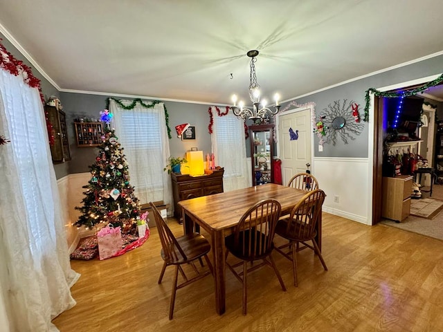 dining space with a chandelier, ornamental molding, and light hardwood / wood-style floors