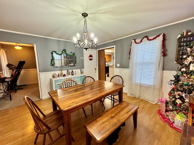 dining space featuring light hardwood / wood-style floors, crown molding, and a chandelier