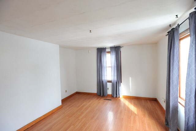 spare room with a wealth of natural light and light hardwood / wood-style flooring