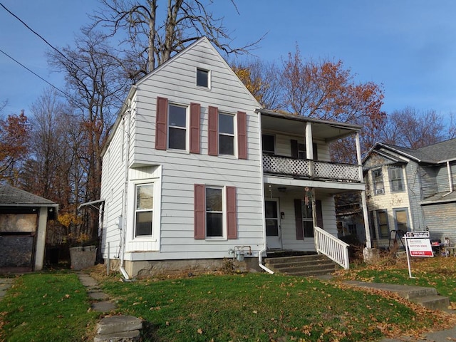 view of front property featuring a front yard, a balcony, and covered porch