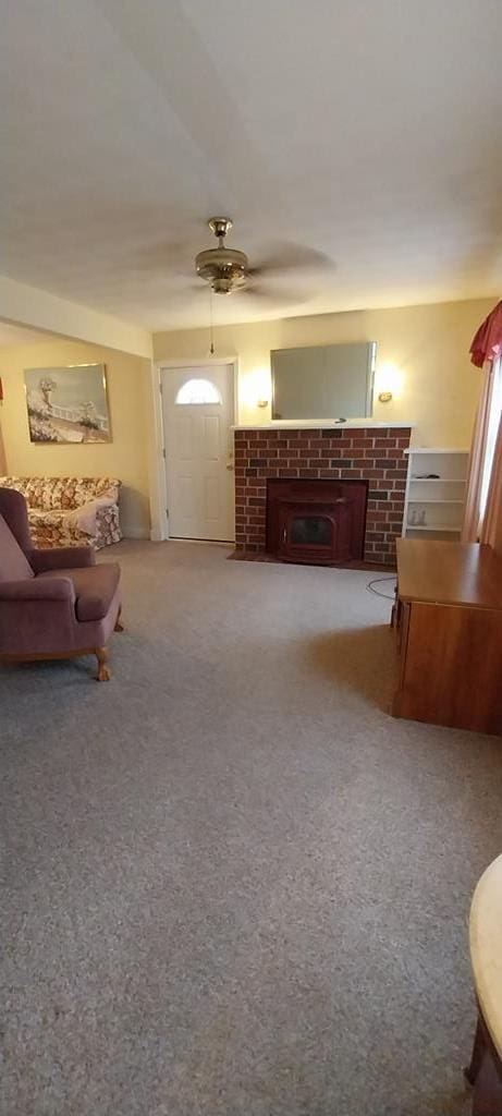 carpeted bedroom featuring a brick fireplace and ceiling fan