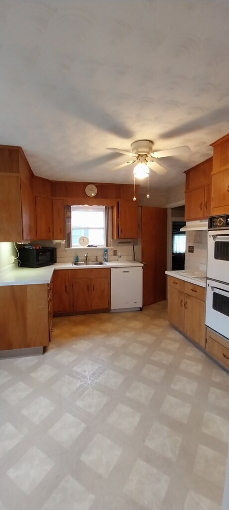 kitchen with white appliances, ceiling fan, and sink