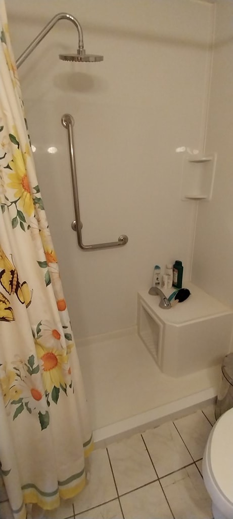 bathroom with tile patterned flooring, a shower with shower curtain, and toilet