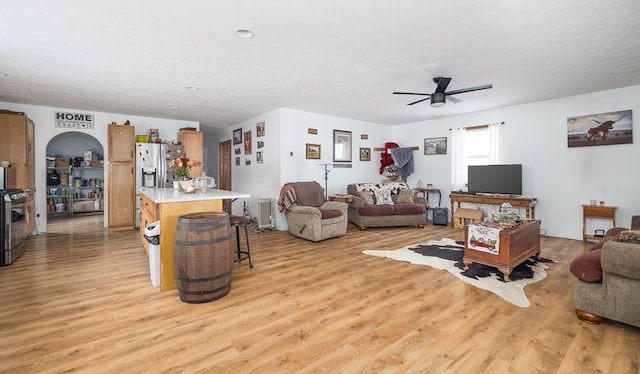 living room with ceiling fan, a textured ceiling, and light hardwood / wood-style flooring